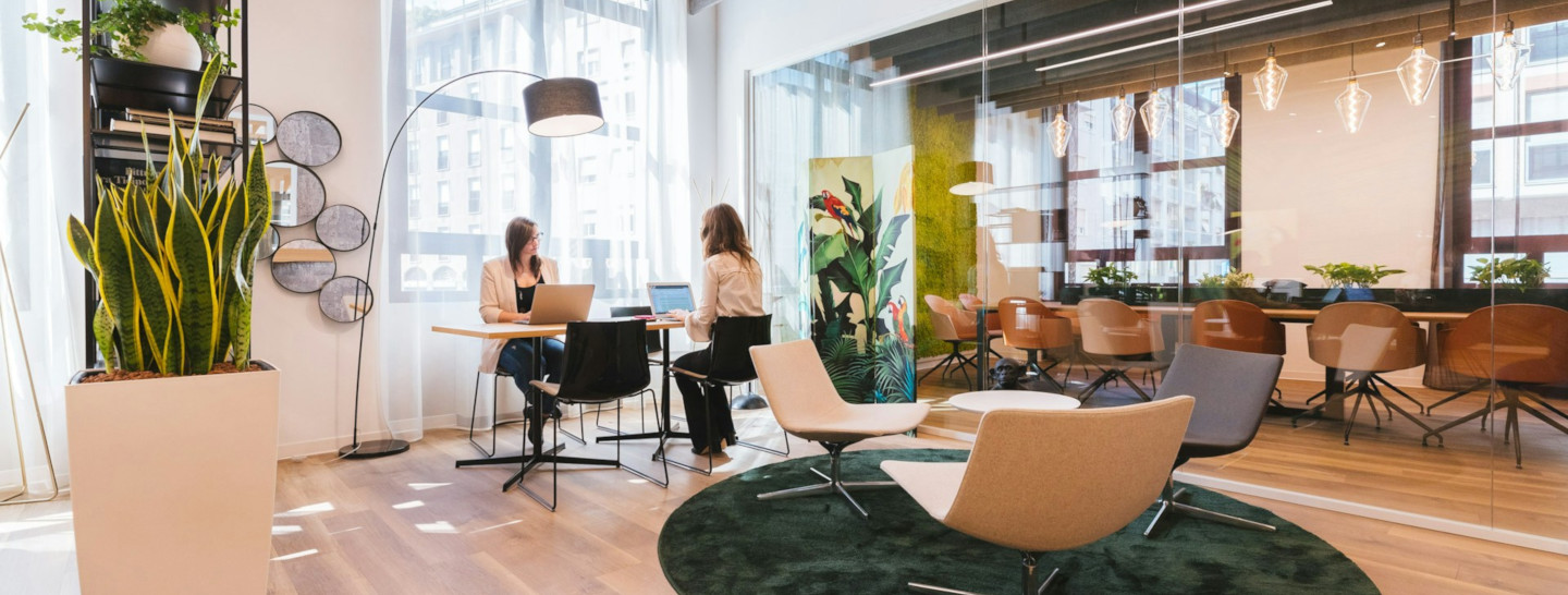 Two women sitting on chairs in coworking space