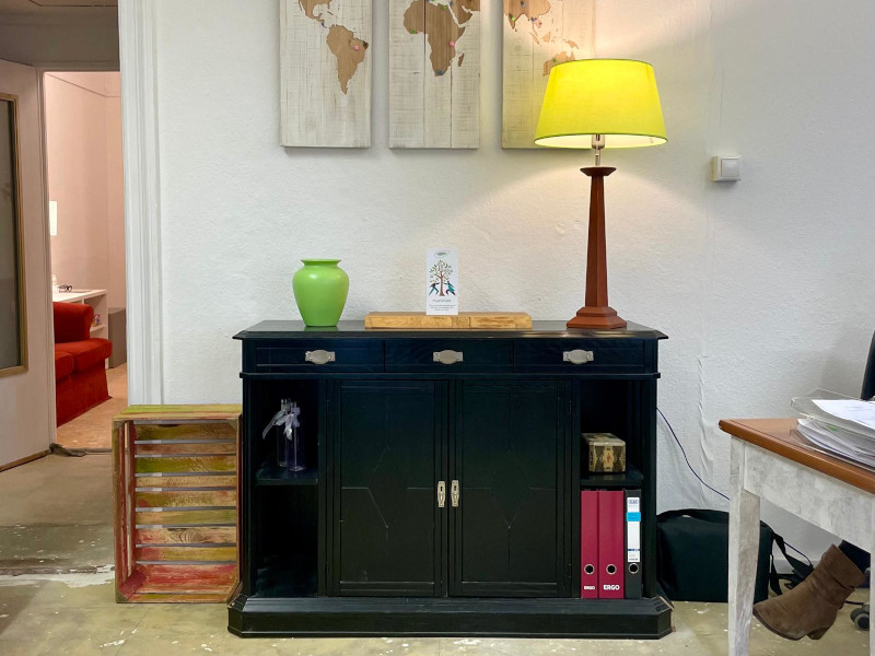 a black cupboard with a yellow lamp on top and a wooden world map in the background
