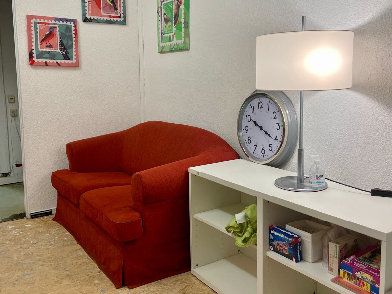 a red sofa next to a white sideboard and a white lamp