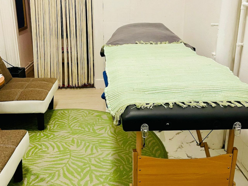 a massage bed and some lounge chairs in a room with a green carpet