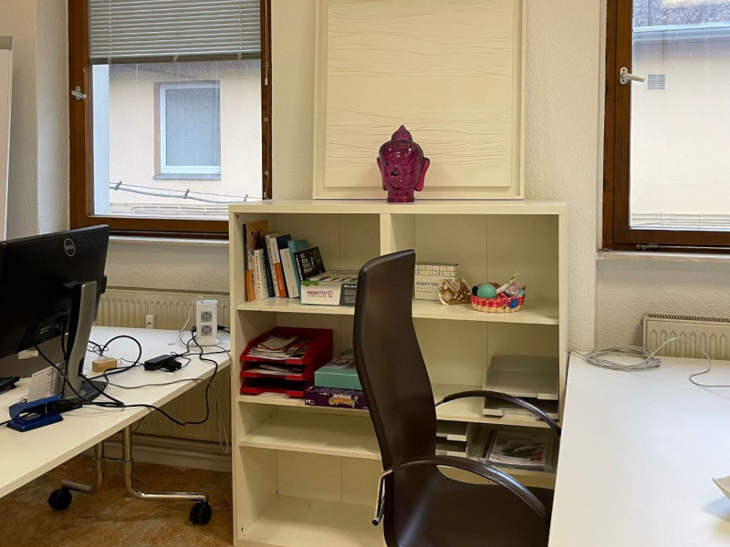 a brown chair and two white desks in a co-working room
