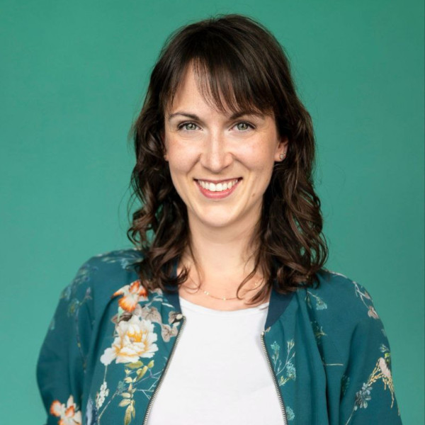Maggan_600x600 Young woman with brown hair in green shirt smiling into camera